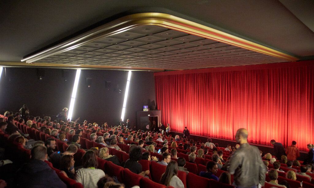 Kinosaal mit rotem Vorhang und Publikum