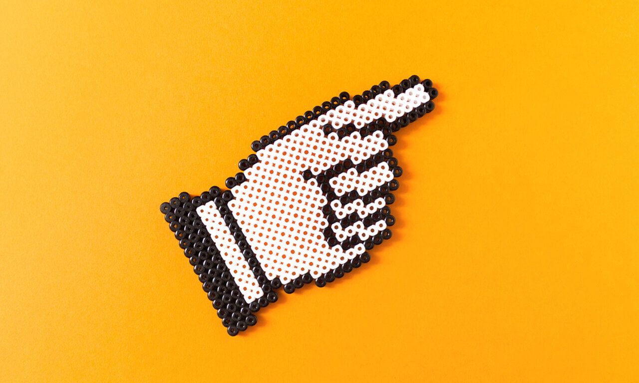 Zeigenfinger aus Bügelperlen auf orange-gelbem Hintergrund