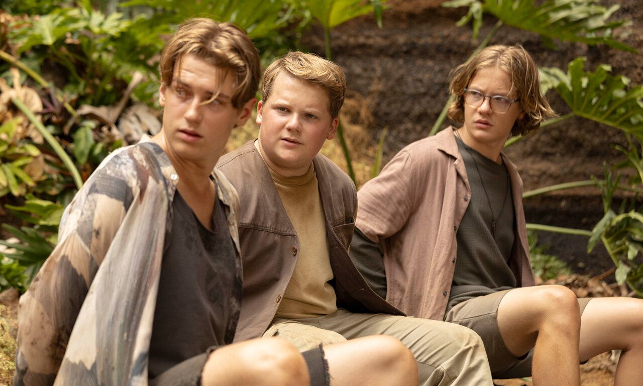 Szene aus dem Film Die drei ??? – Toteninsel, drei Jungs sitzen in der Natur