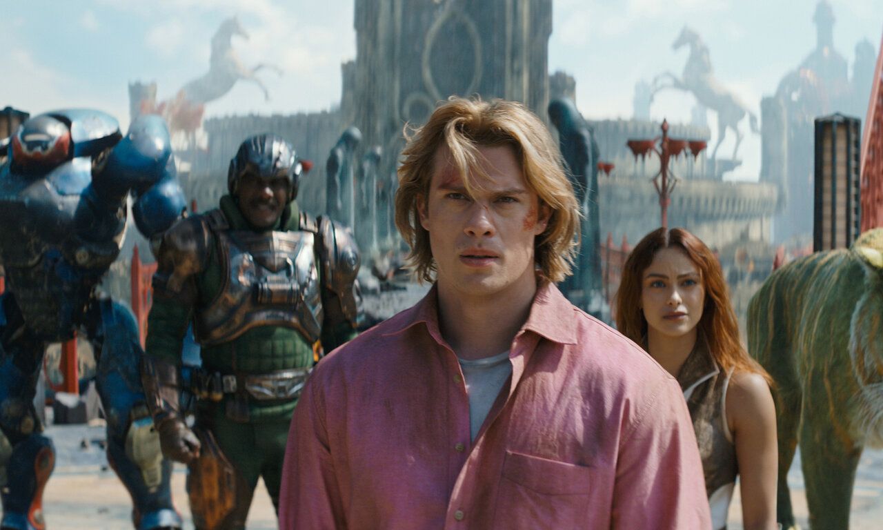 Szene aus dem Film Masters of the Univers, ein Mann steht im Vordergrund, hinter ihm eine Frau, ein Kämpfer und ein Roboter