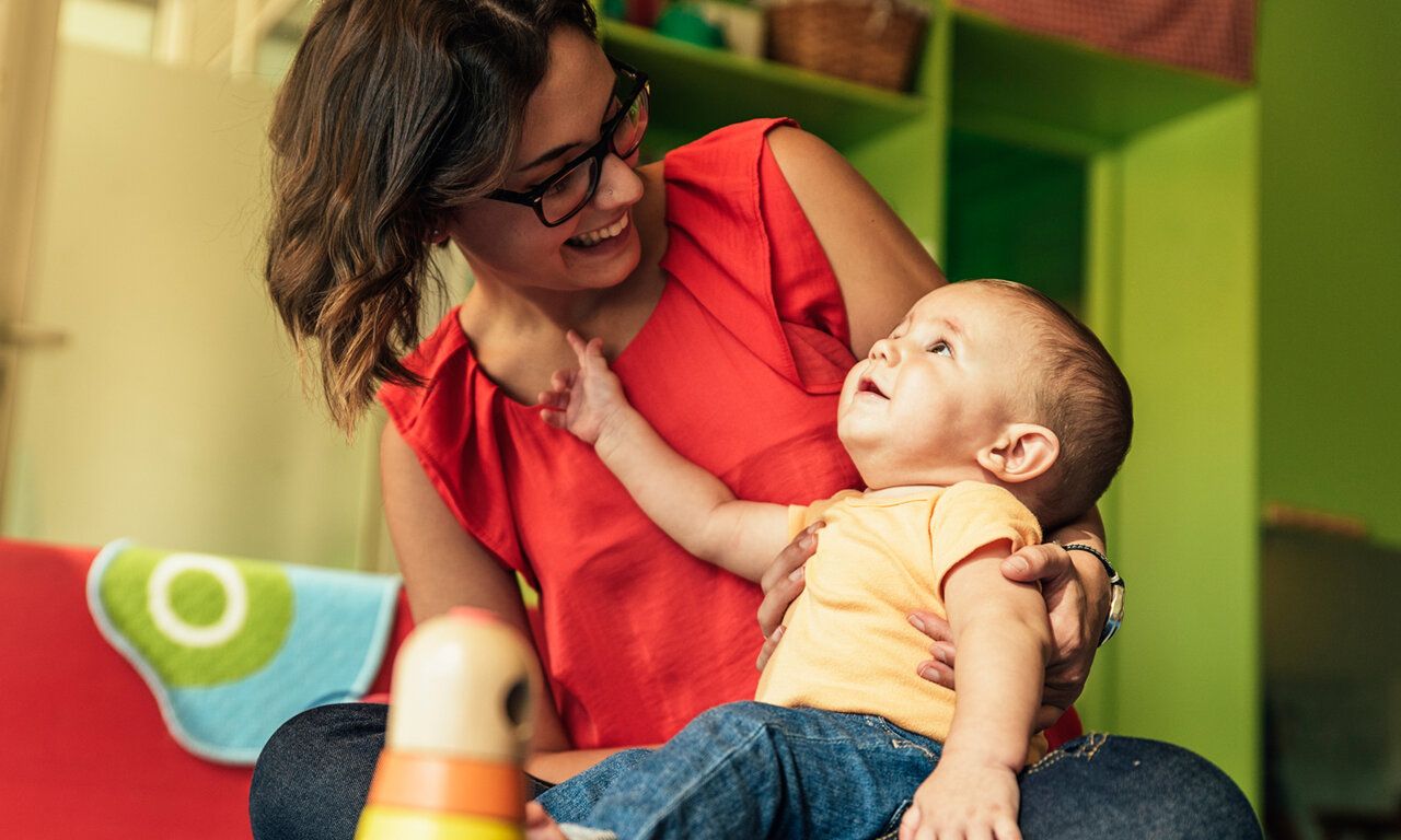 Frau hat Baby auf dem Schoß, beide gucken sich an