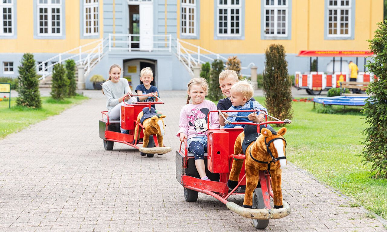 Kinder mit Fahrzeugen vor Schloss Beck