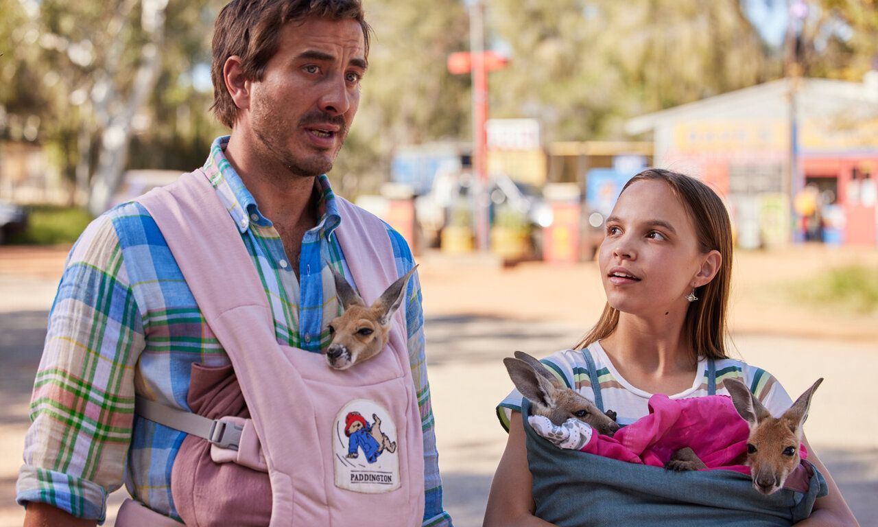 Szene aus dem Film Lilly und die Kängurus, ein Mann und ein Mädchen stehen nebeneinander und sprechen, beide tragen Kängurus bei sich