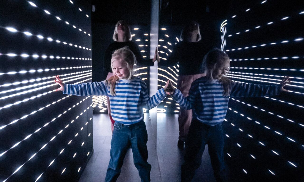 Mädchen im Kunstpalast, in einem dunklen Raum mit leuchtender Installation