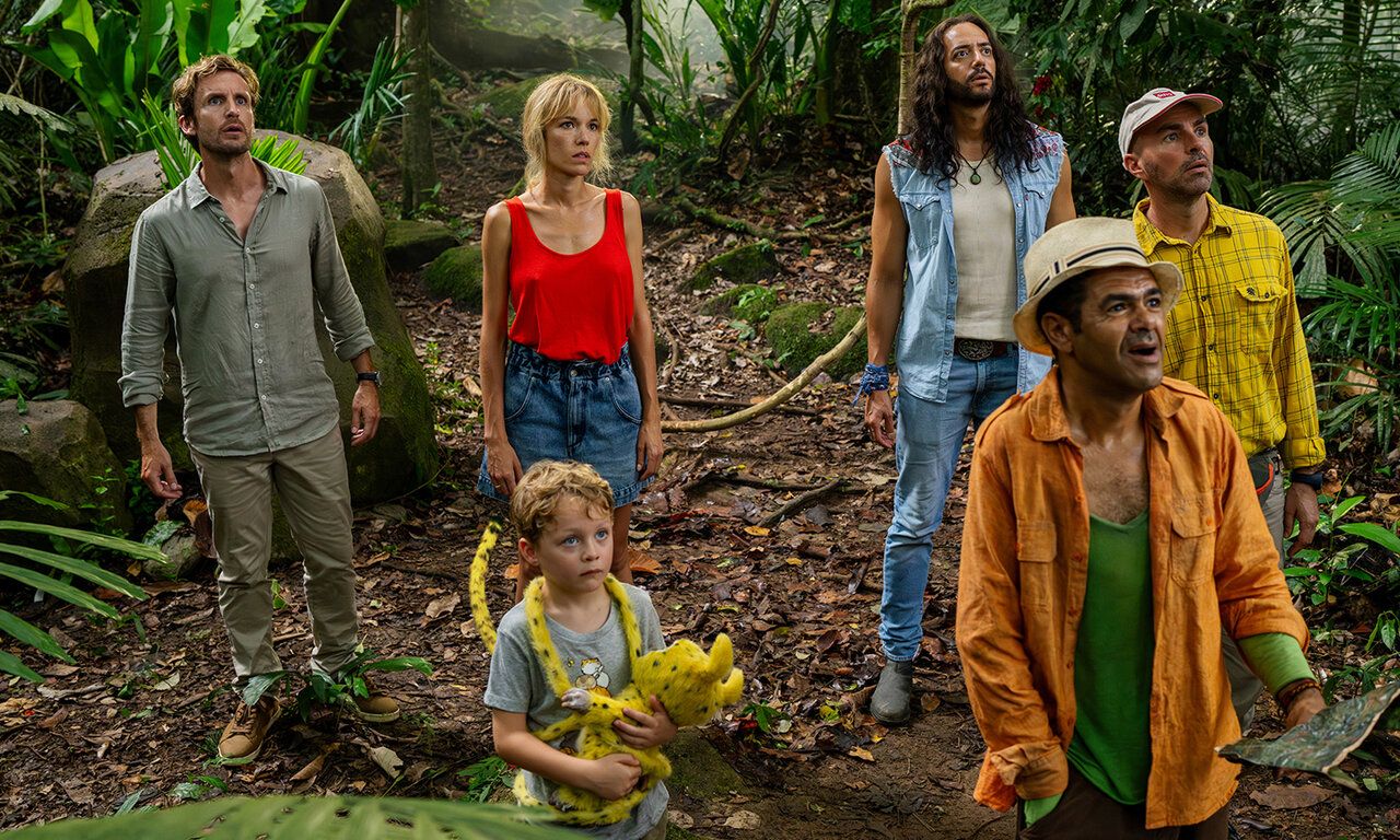 Szene aus dem Film Marsupilami, vier Erwachsene und ein Kind mit Marupilami-Plüschtier stehen in einem Urwald und gucken nach oben