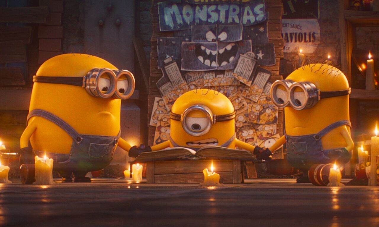 Szene aus dem Film Minions und Monster, drei Minions lesen in einem alten Buch