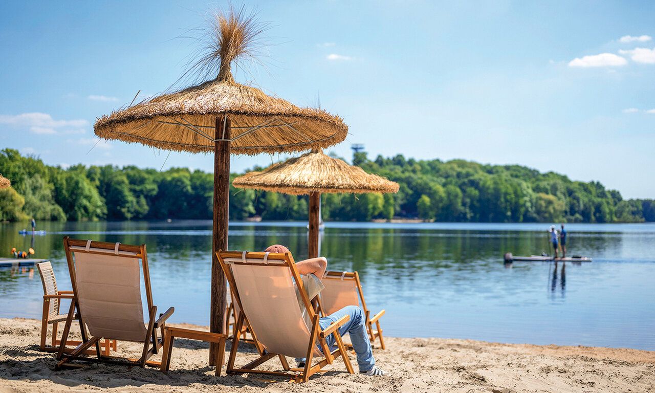 Sonnenschirm und Liegenstühle am Strand der Sechsseenplatte