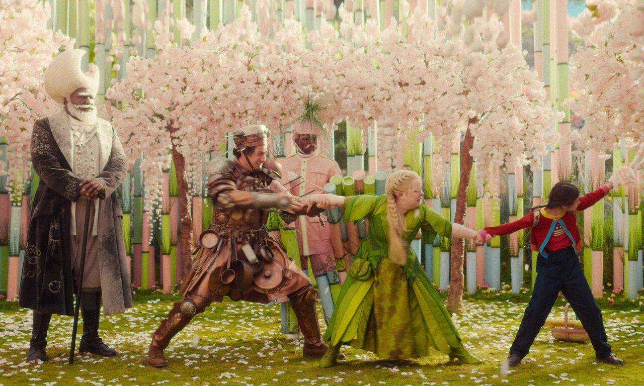 Szene aus dem Film Der Wunderweltenbaum, verschiedene Personen stehen in einer Art Märchenwald