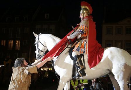 St. Martin sitzt auf seinem Pferd, teilt den Mantel, gibt ihn dem Bettler, abends vor dem Düsseldorfer Rathaus