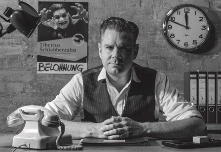 Guido Hoehne sitzt in einem Büro am Schreibtisch, Schwarz/Weiß-Foto