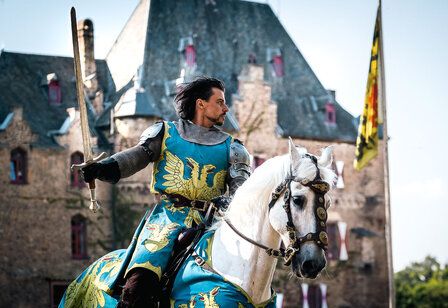 Ritter reitet auf seinem Pferd vor Burg Satzvey