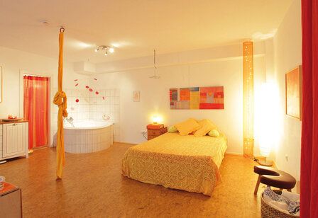 Geburtszimmer des Geburtshauses Düsseldorf, Raum mit Bett, Gebärwanne, Seil, Hocker, in Rot- und Orangetönen gehalten