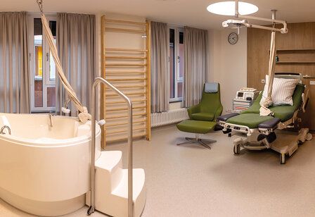 Kreißsaal des Klinikums Leverkusen mit Badewanne, Bett, Sprossenwand, CTG-Gerät, Seil und Sessel