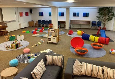 Spielbereich beim Elterncafé der Rheinkirche mit Sofas und verschiedenen Spielzeugen..