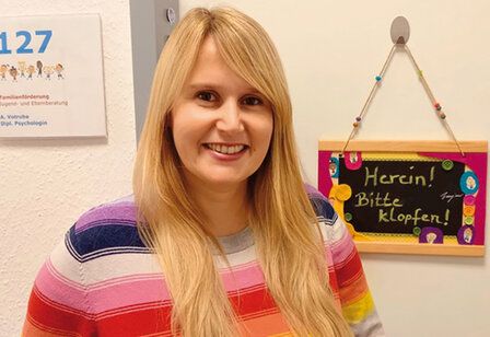 Porträt von Alina Votruba mit gestreiftem Pullover vor Zimmertür