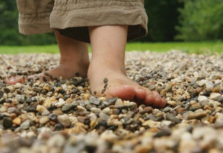 Kinderfüße, die über Kieselsteine laufen
