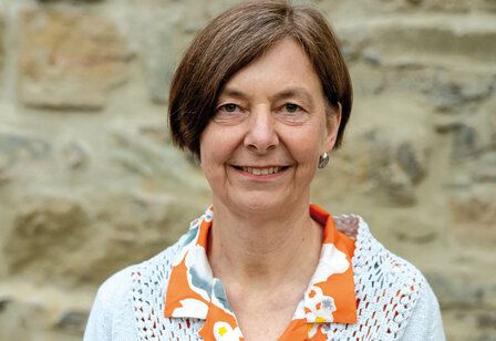 Porträt von Dr. Elisabeth Müller, im Hintergrund Steinmauer