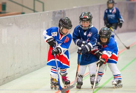 Drei Kinder spielen Inlineskate-Hockey