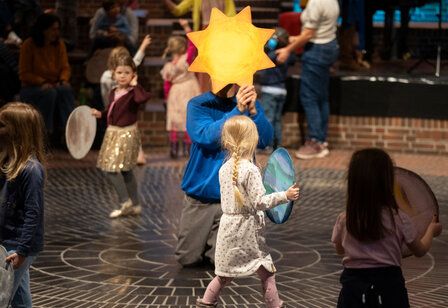 Familienmusikwoche Plutino, Kinder laufen herum, ein Mann kniet und hält einen Stern hoch