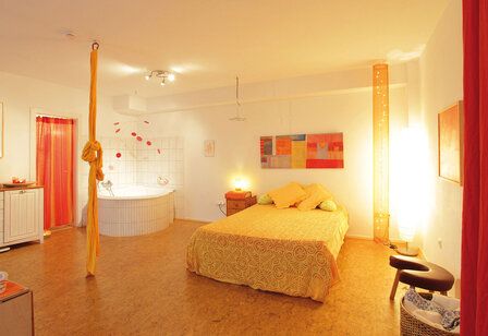 Geburtszimmer des Geburtshauses Düsseldorf, Raum mit Bett, Gebärwanne, Seil, Hocker, in Rot- und Orangetönen gehalten