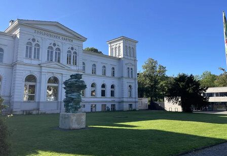 Das gebäude des Zoologischen gartens Wuppertal, davor ein Rasen mit einer Skulptur