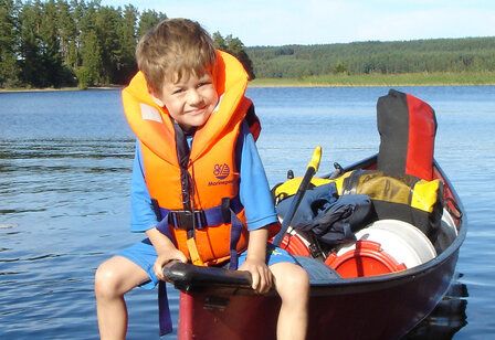 Junge mit Schwimmweste in einem Boot auf einem See