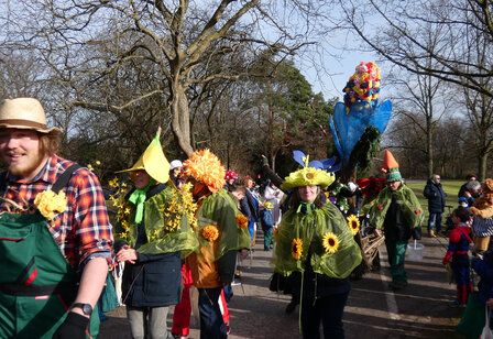 Als Bauern und Blumen verkleidete Leute ziehen durch den Südpark