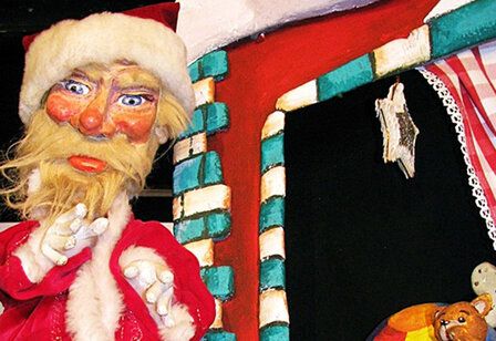 Handpuppe vom Weihnachtsmann vor einen Haus