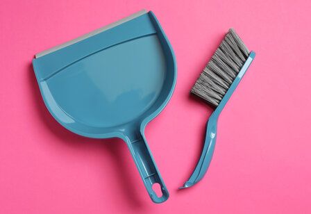 Blaues Kehrblech und Kehrbesen auf pinkem Huntergrund