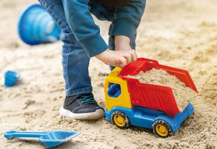 Kind spielt mit Spielzeug-LKW im Sandkasten