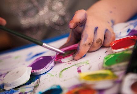 Detailaufnahme: Kinderhand mit Pinsel und Wasserfarbe
