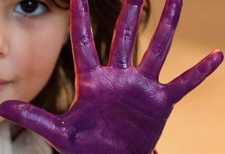Kind zeigt lila Handfläche in die Kamera