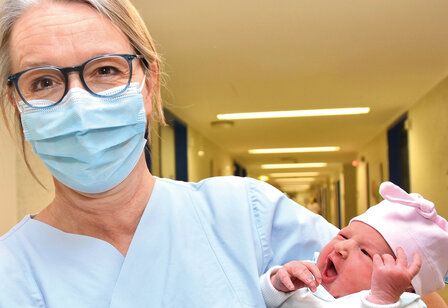 Porträt einer Hebamme mit Neugeborenem