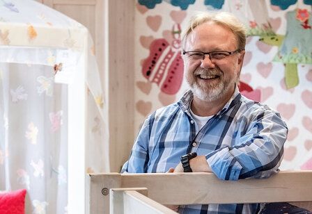 Porträt von Klaus Maiwald, der in seinem Geschäft hinter einem Hochbett steht und lacht