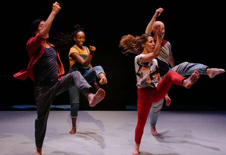 Vier Tänzer und Tänzerinnen tanzen auf einer Bühne