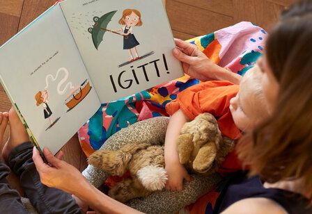 Eine Frau liest Kindern aus einem Bilderbuch vor, fotografiert von oben