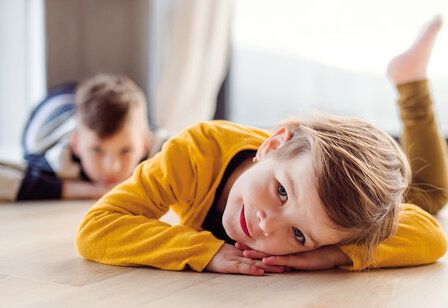 Zwei Kinder liegen auf dem Fußboden herum und machen nichts