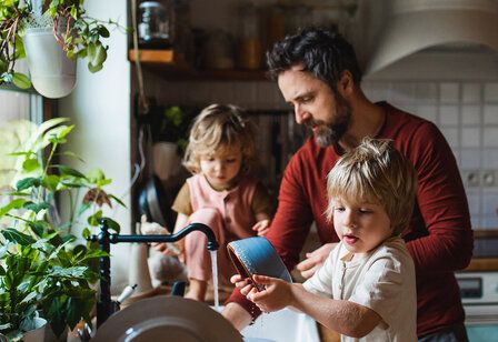 Vater mit zwei Kindern in der Küche beim Abspülen
