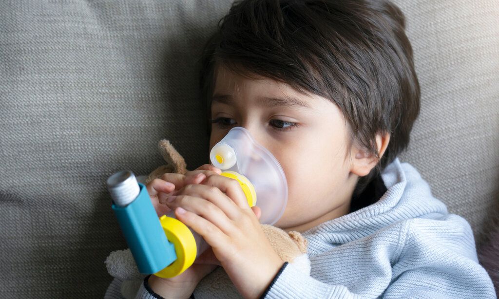 Kind auf Sofa mit Asthmaspray