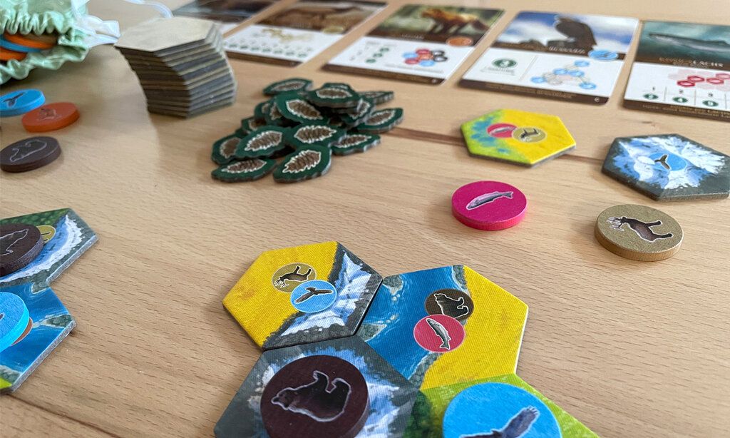 Spielkarten und -plättchen vom Spiel Cascadia liegen auf einem Tisch