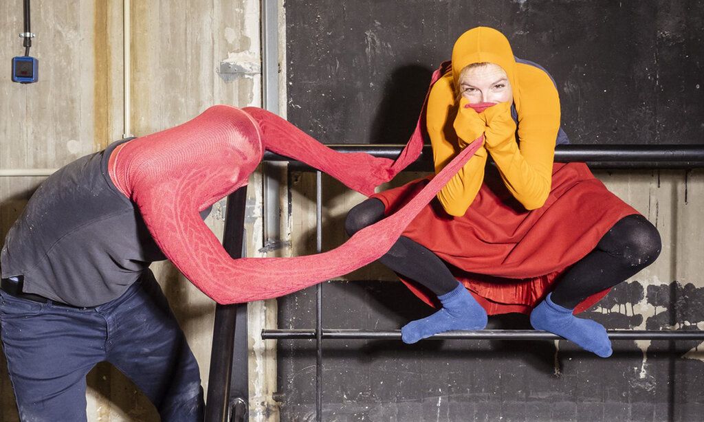 Schauspieler und Schauspielerin tragen Strumpfhosen über den Köpfen und spielen miteinander