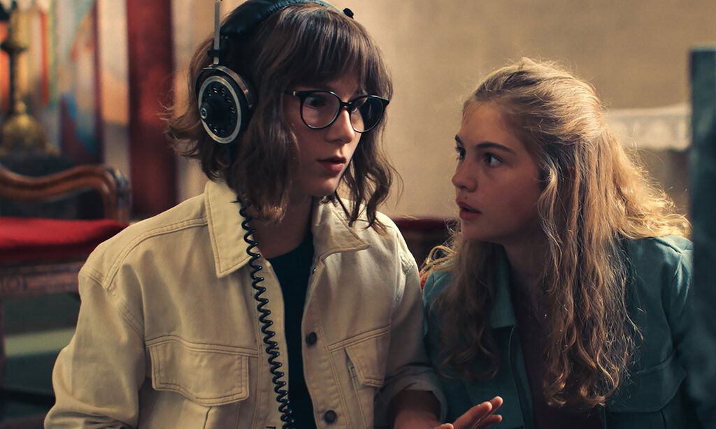Zwei Mädchen stehen nebeneinander, eine trägt einen Kopfhörer und guckt erstaunt