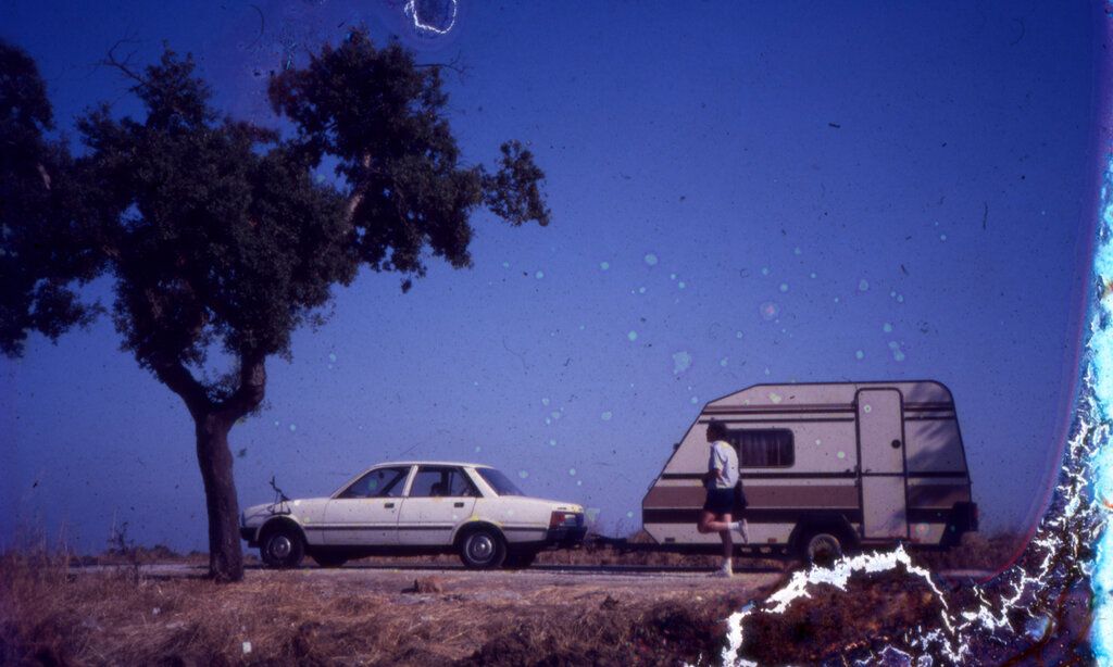 Ein altes Foto von einem Baum, einem Auto mit Wohnwagen und einem Jogger, das Bild ist am rechten Rand zerstört