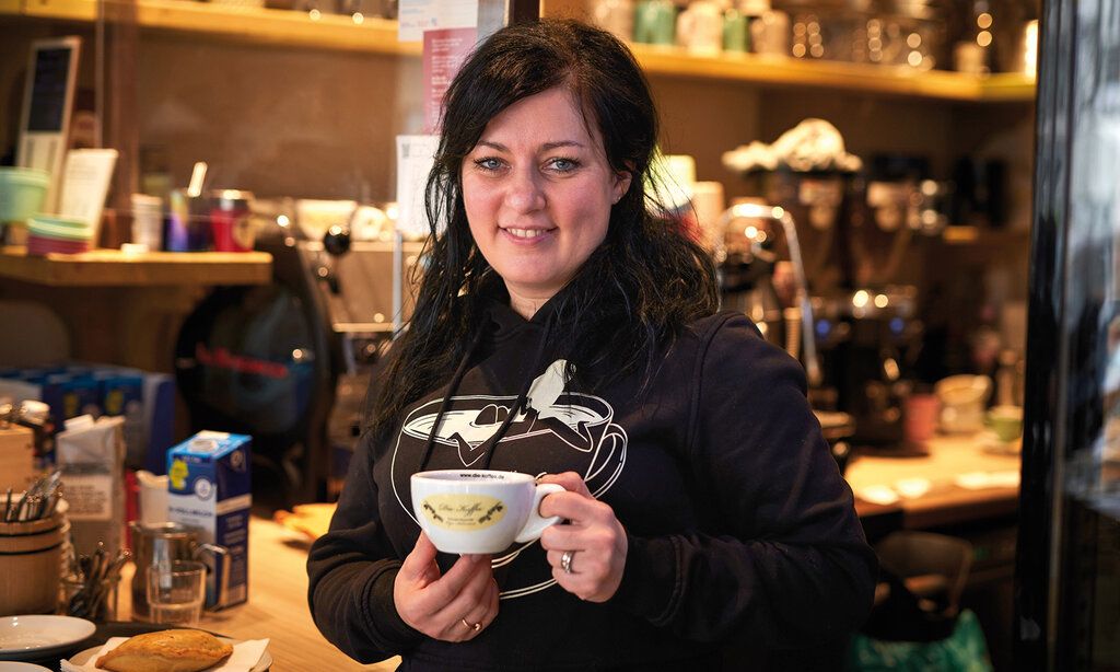 Frau steht mit einer Kaffeetasse in einem Lokal