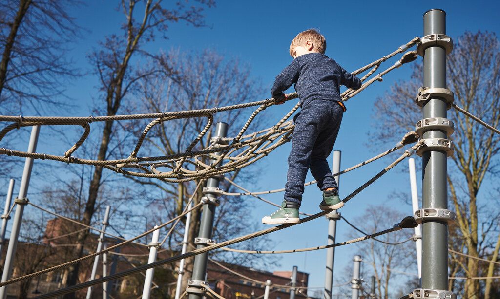 Junge klettert auf einer Seilpyramide auf einem Spielplatz in Pempelfort