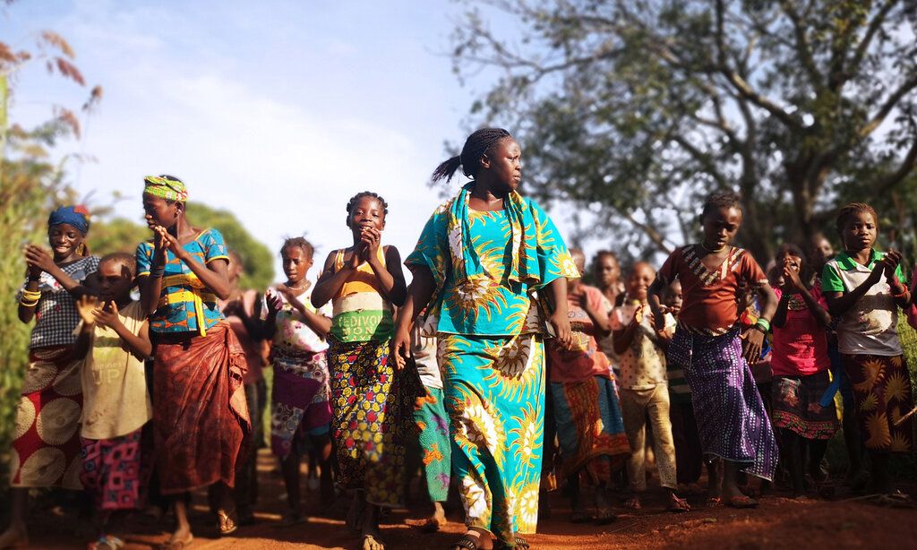 Junge afrikanische Frauen tanzen bunt gekleidet draußen