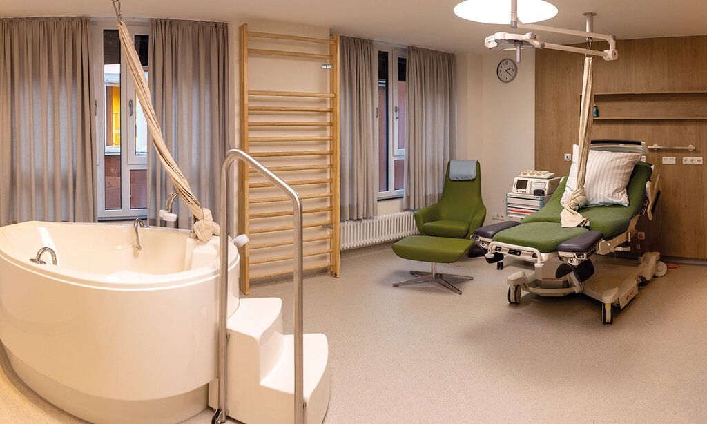 Kreißsaal des Klinikums Leverkusen mit Badewanne, Bett, Sprossenwand, CTG-Gerät, Seil und Sessel