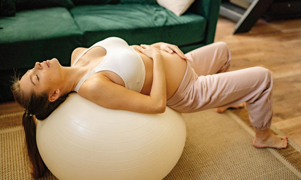 Eine Schwangere entspannt auf einem Pezziball