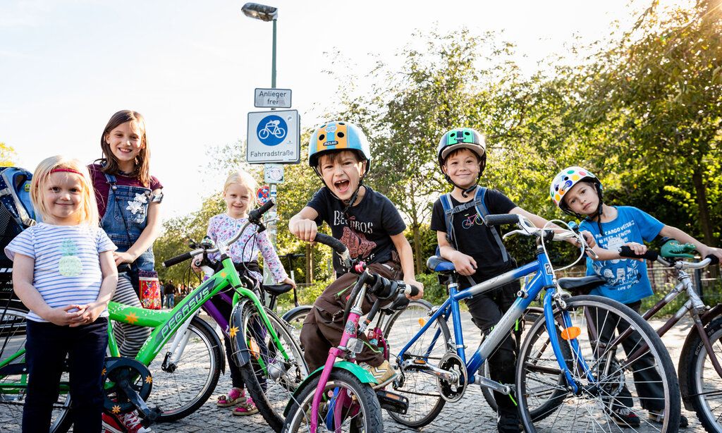 drei Mädchen und drei Jungen stehen mit ihren Fahrrädern auf einer Straße