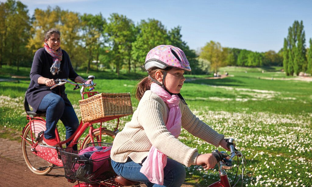 Mutter und Tochter fahren mit den Rädern durch den Südpark im Sommer